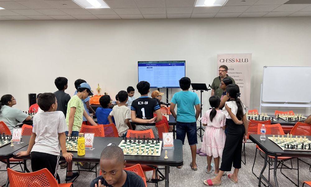 CHESSKLUB students playing chess with a tutor.