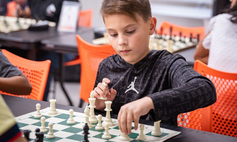 Young CHESSKLUB student making a chess move on the board