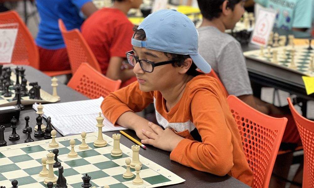 CHESSKLUB student analyzing the board and recording moves during a game