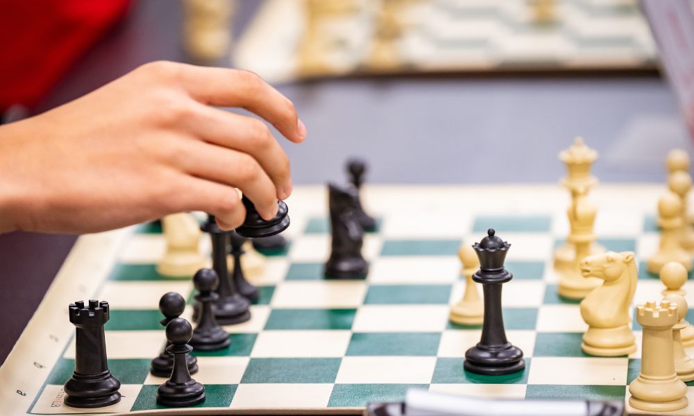 chess-pieces-powerful-than-queen-and-king Player moving a chess piece on a chessboard during a game at CHESSKLUB.