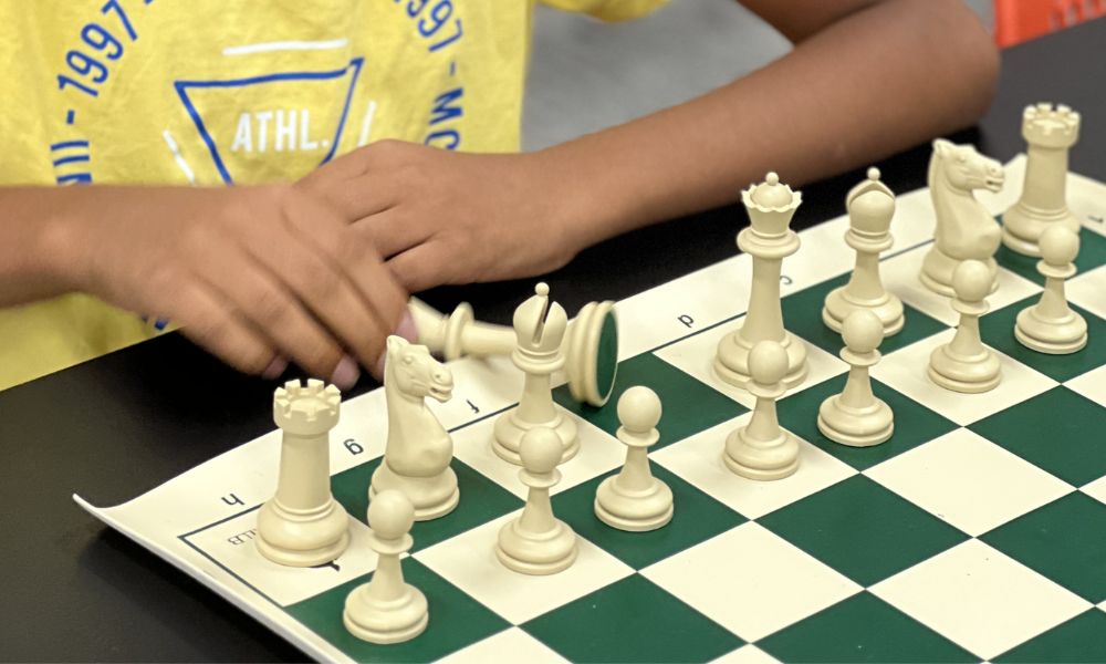 A CHESSKLUB student with a captured white chess piece on a green board
