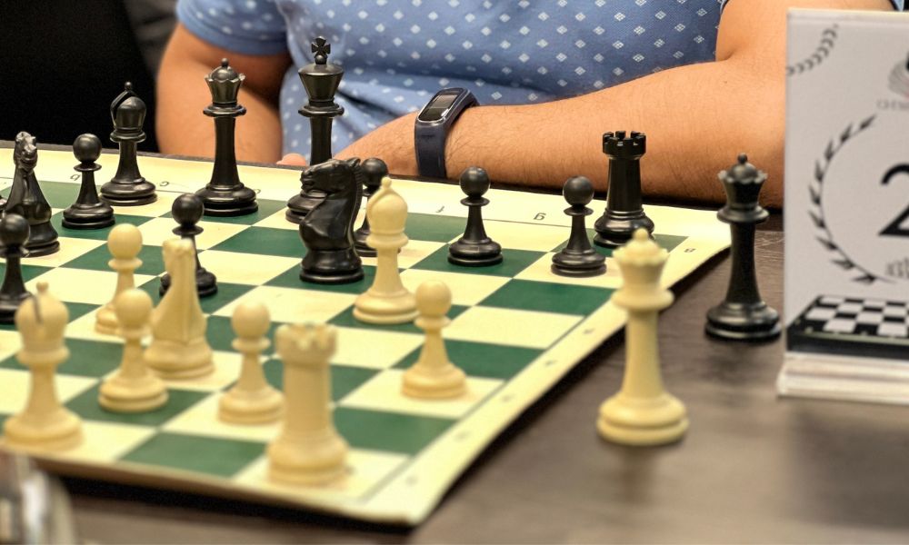 CHESSKLUB player observing black and white chess pieces on a board